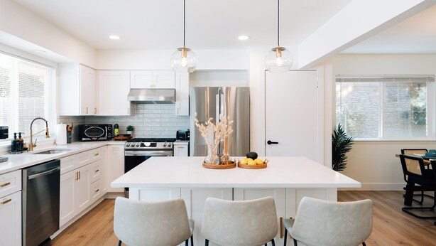 Una cocina moderna con armarios blancos, una isla central e iluminación colgante.