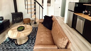 Un vaste espace de vie doté d’un plafond en bois, d’un escalier, d’une cuisine moderne et d’un coin salon confortable.