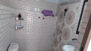 A bathroom with white tiled walls, a toilet, a sink, and a shower. - Hotel Amodou (Tinghir)