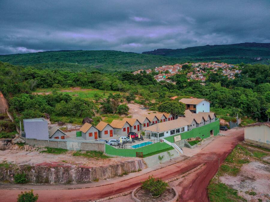 A hotel with a swimming pool, surrounded by lush greenery and a hilly landscape.