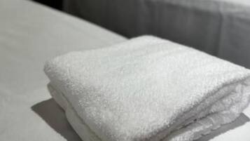 Una habitación de hotel con dos camas, cada una con ropa de cama y almohadas blancas.