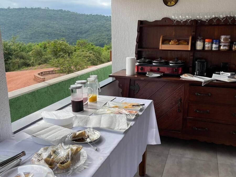A dining area with a table set for breakfast, a coffee machine, and a view of the mountains.