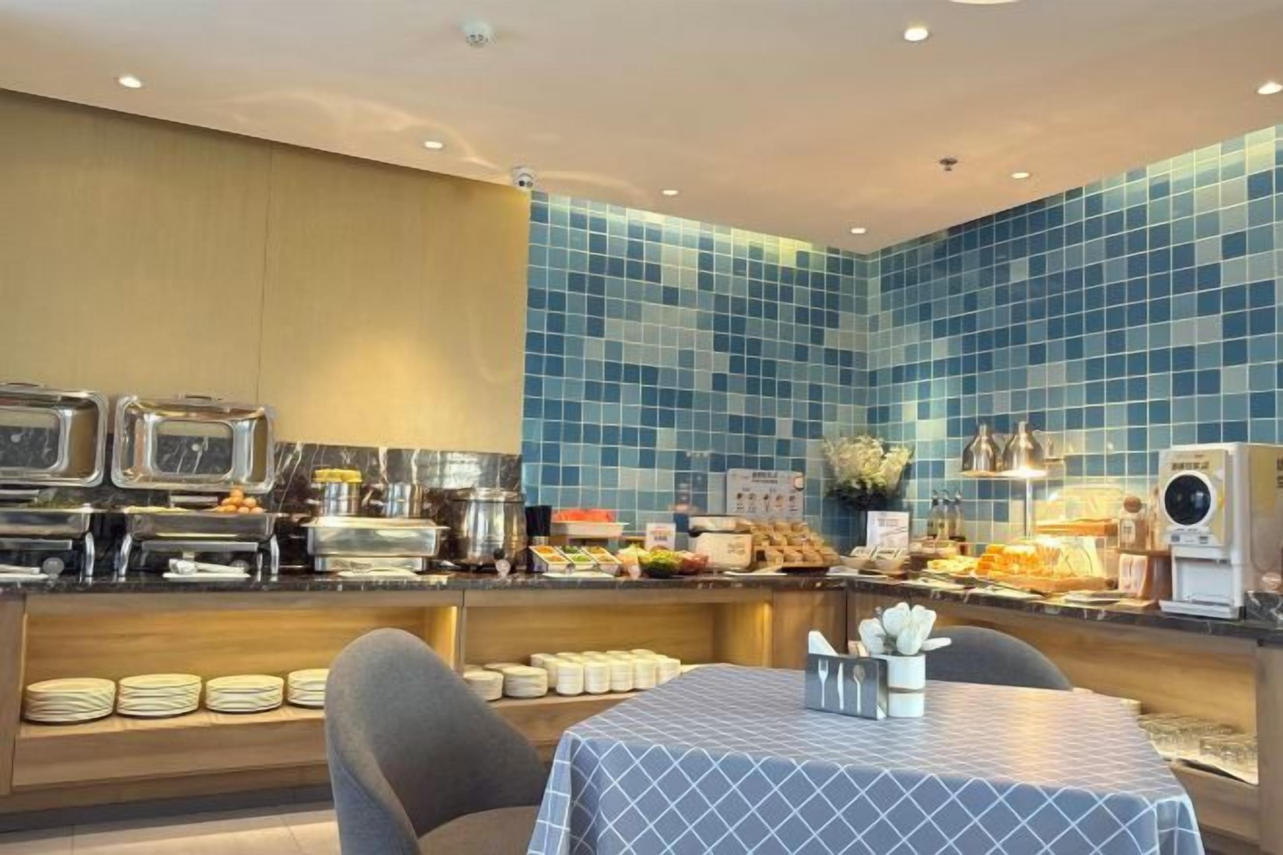 Ein Frühstücksbereich mit Buffet, eine Sitzecke mit Tisch und einer gefliesten Spritzschutzwand.