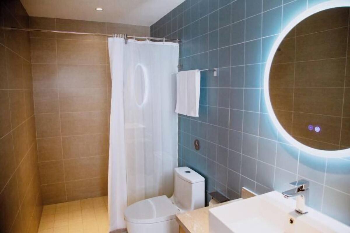 Un baño con ducha, inodoro, lavabo y un espejo grande.