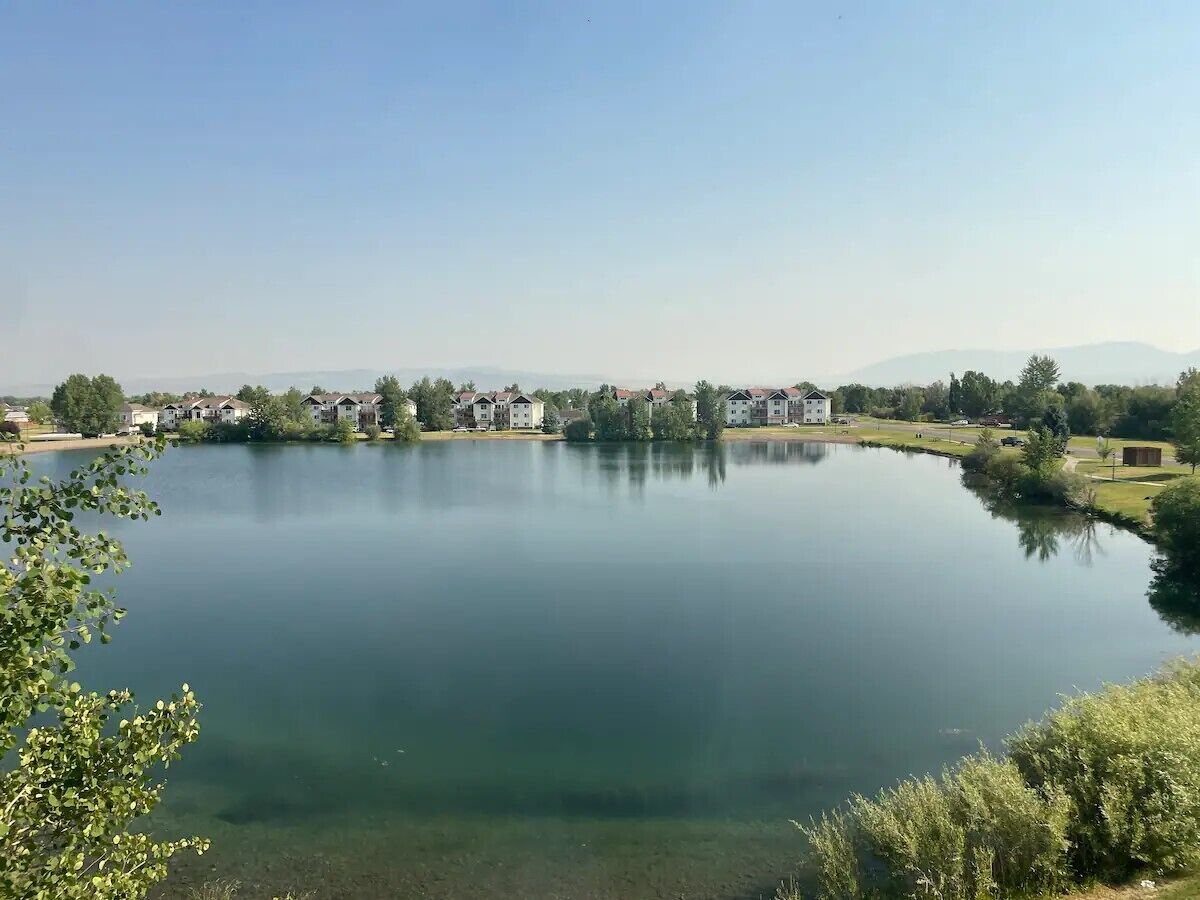 Una extensa masa de agua que refleja claramente edificios y árboles.