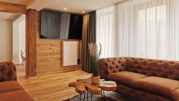 A modern living room with a brown sofa, wooden flooring, a wooden coffee table, and a TV mounted on the wall. - Alpenperle im Zentrum von Erfurt/nähe Domplatz (Erfurt)
