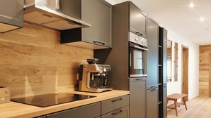 A modern kitchen with dark cabinetry, a built-in espresso machine, and a wooden countertop. - Alpenperle im Zentrum von Erfurt/nähe Domplatz (Erfurt)