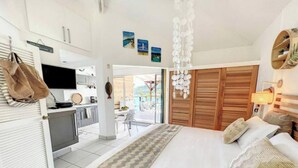 Une chambre moderne avec un grand lit, une petite kitchenette et un placard avec une porte coulissante en bois.
