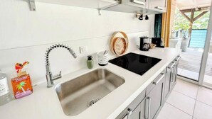 Une cuisine moderne dotée d’un évier à deux bacs, d’appareils électroménagers en acier inoxydable et offrant une vue sur l’extérieur.