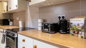 Een keuken met witte kastjes, een zwarte broodrooster, een koffiezetapparaat en een bord met de tekst 'Welcome to Herefordshire'.
