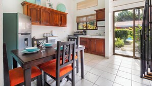Een moderne keuken met houten kastjes, een eettafel met oranje stoelen, en een groot raam met uitzicht op de omgeving.