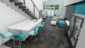 Una cocina moderna con encimera blanca, taburetes de bar color turquesa y una escalera con escalones negros y de madera.