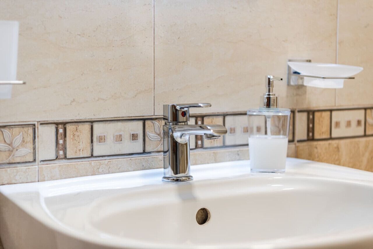 A bathroom sink with a chrome faucet and a soap dispenser.