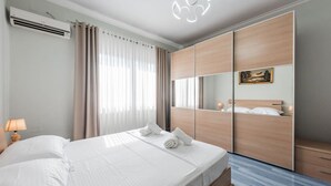 A modern hotel room with a large bed, a wardrobe, a mirror, and an air conditioning unit. - The Old-Clock Apartment by PikHost (Shkodër)