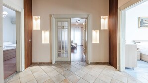 A hotel hallway with a tiled floor, wooden paneling, and wall-mounted lighting fixtures. - The Old-Clock Apartment by PikHost (Shkodër)
