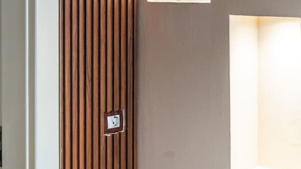 A modern interior with vertical wooden slats and recessed wall lighting. - The Old-Clock Apartment by PikHost (Shkodër)