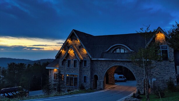 A stone house with a large arched entrance and a driveway.