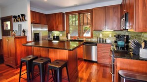 A modern kitchen with wooden cabinets, stainless steel appliances, and a central island with stools.