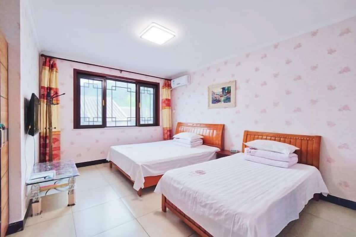 A room with two beds, a small table, and a window with curtains.