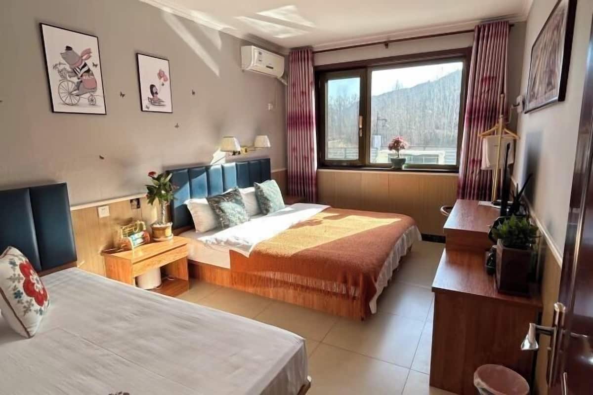 A hotel room with a bed, bedside table, lamp, and a view of mountains through the window.