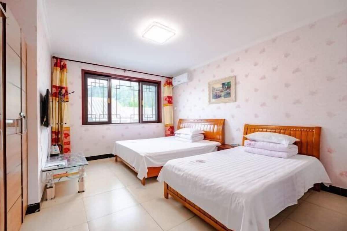 A room with two beds, a window, a TV, and a small table.