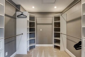 A walk-in closet with open shelving, a hanging rod, and a mirrored closet door.