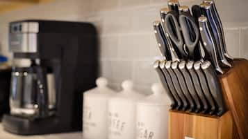 A kitchen counter with a coffee maker, a knife block, and containers labeled 'SUGAR' and 'COFFEE'.