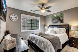 A bedroom with a bed, bedside tables, a window, a ceiling fan, and a clock on the wall. - Modern 5BR Home | Chef’s Kitchen | BBQ | Sleeps 10 (Stateline)