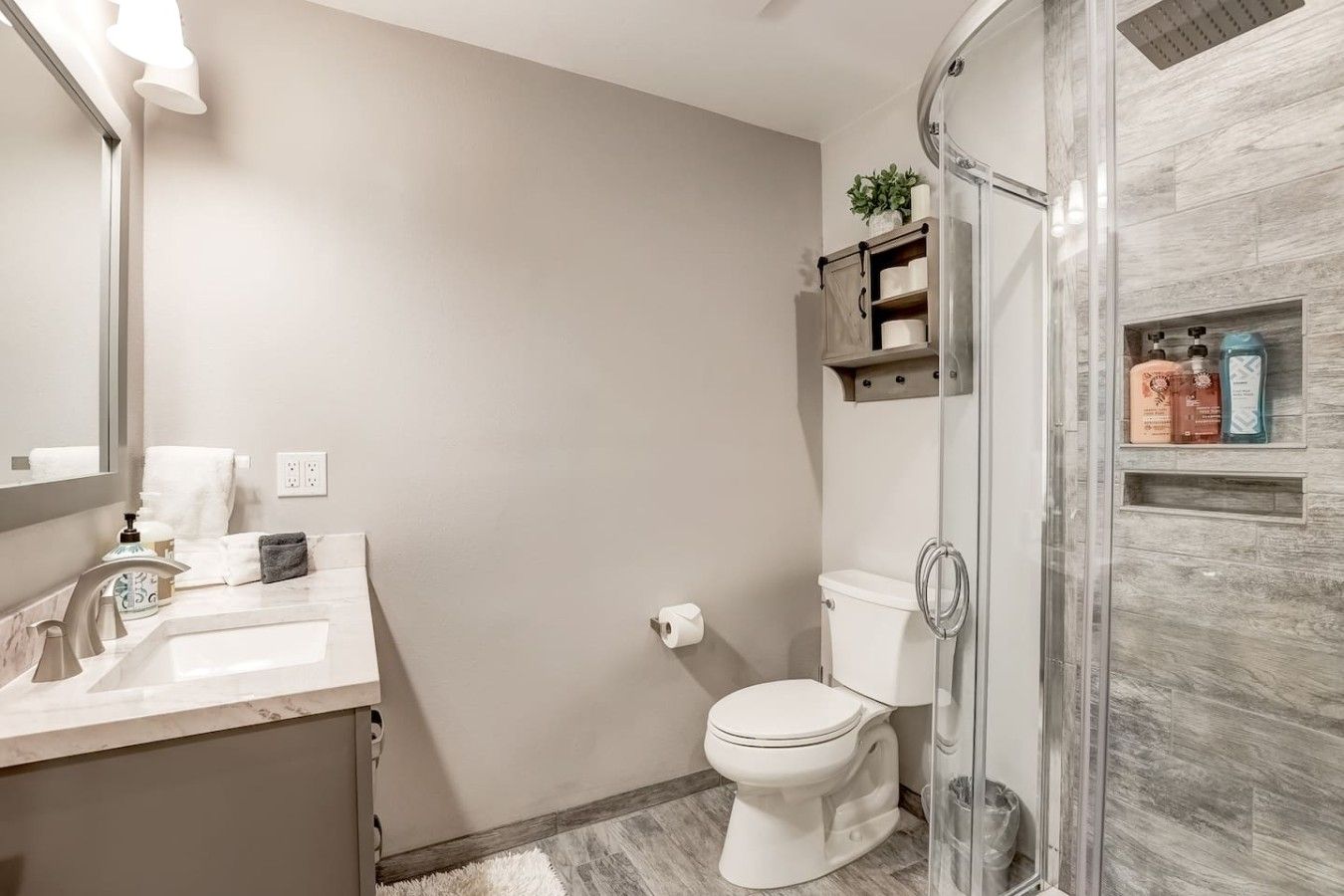 Une salle de bain comprenant des toilettes, un lavabo, un miroir et un espace douche.