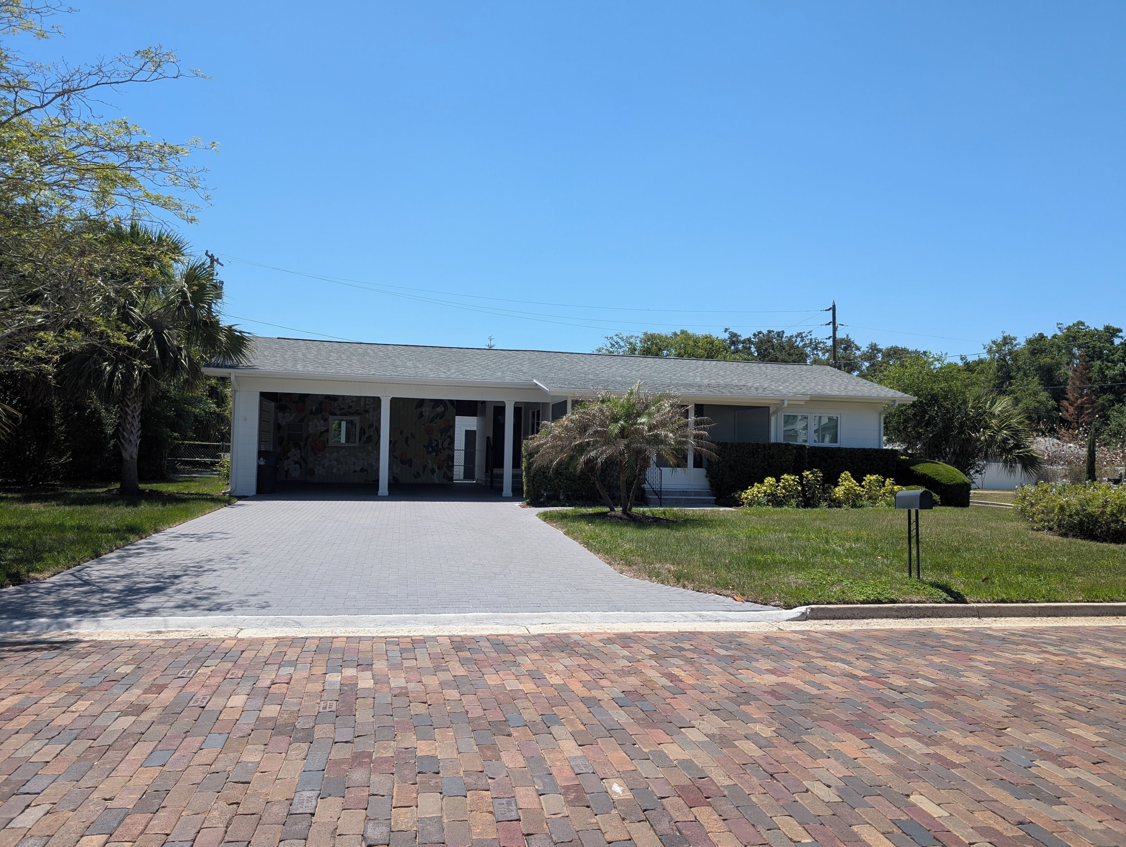 A two-story house with a covered porch, a paved driveway, and a well-maintained lawn.