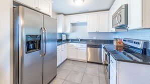 A modern kitchen with white cabinets, stainless steel appliances, and a tiled backsplash. - Downtown Winter Garden bungalow with private putting green and fire pit (Winter Garden)