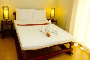 A neatly made bed with a white sheet and pillows, a decorative swan towel, and two bedside lamps. - Levantin Boracay (Boracay Island)