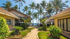 A resort with a pathway leading to a beach, surrounded by palm trees and buildings with large windows. - Levantin Boracay (Boracay Island)
