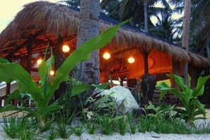 Una costruzione con tetto di paglia e un cartello, immersa nella vegetazione tropicale.