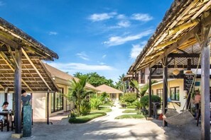 Un resort con estructuras de techo de paja, un sendero central y una hamaca.