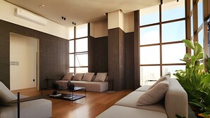 Ein modernes Wohnzimmer mit einer Sofagarnitur, einem Couchtisch und einem großen Fenster mit Blick auf die Stadt.