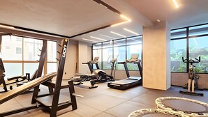 Ein modernes Fitnessstudio mit verschiedenen Trainingsgeräten, großen Fenstern und einem hellen, großzügigen Raumlayout.