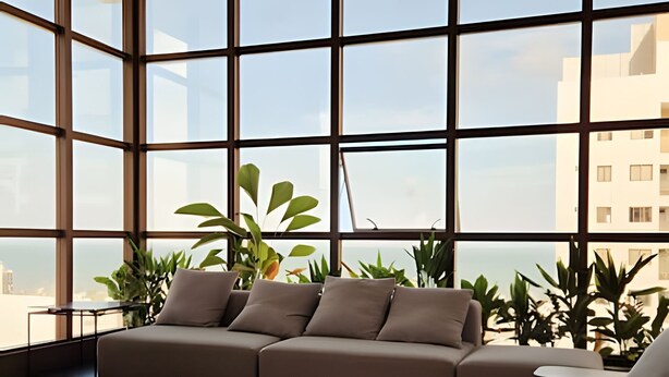 Ein modernes Wohnzimmer mit großem Fenster, einer Couch und verschiedenen Pflanzen.