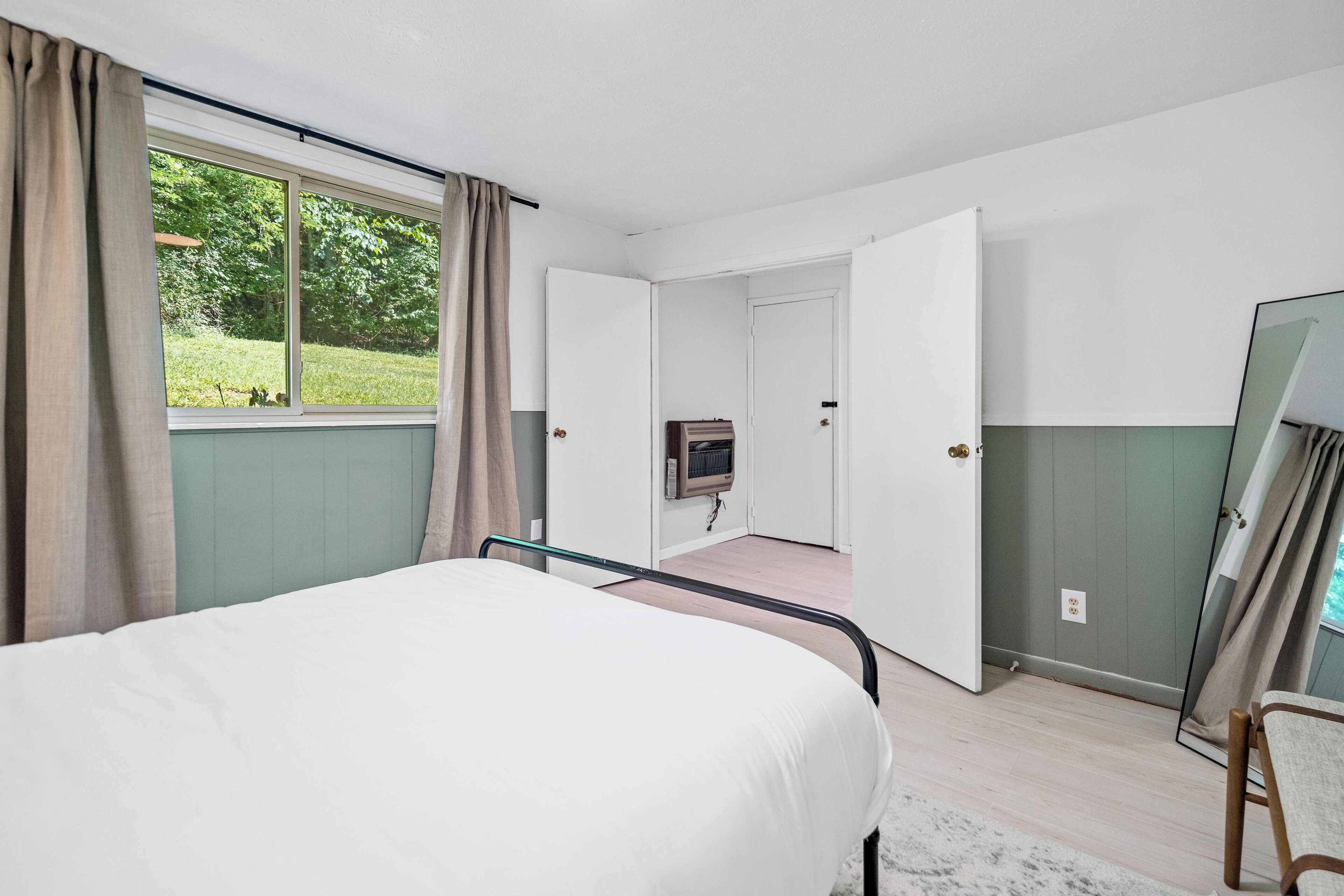 A bedroom with a bed, a TV, and a mirror.