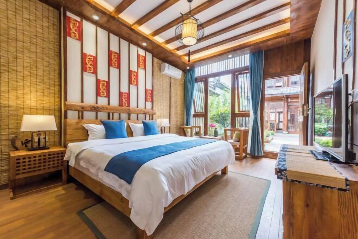 Un dormitorio japonés tradicional con una cama grande, cabecera de madera y puertas correderas que dan a un balcón.