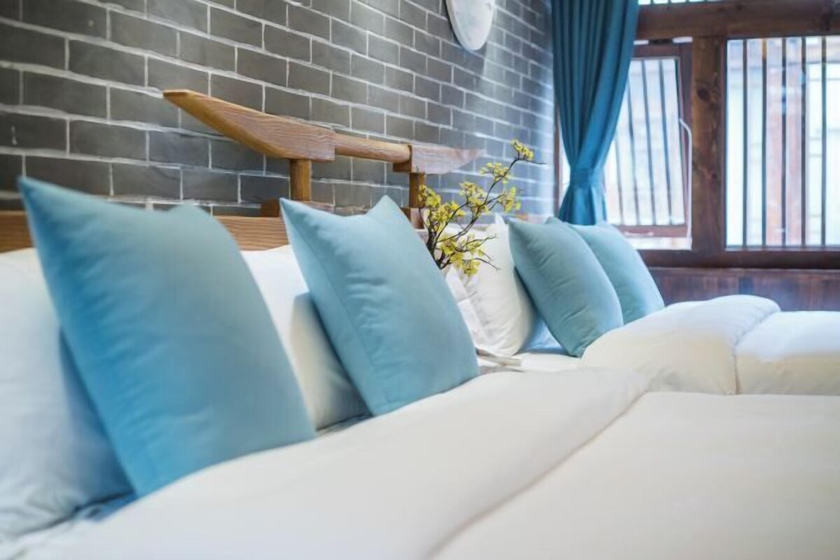 A bed with blue and white pillows, a wooden headboard, and a small plant.