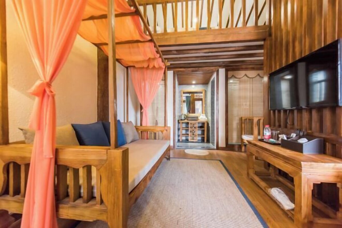 A room with a wooden bed, a TV, and a desk.