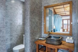 A bathroom with a marble wall, a wooden vanity, a large mirror, and a white toilet. - Yuetu Shishanju, Lijiang Ancient City (Lijiang)
