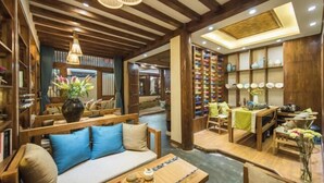A cozy interior with wooden furniture, a sofa with blue cushions, a dining area, and shelves with pottery. - Yuetu Shishanju, Lijiang Ancient City (Lijiang)