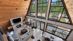 A modern loft-style living space with a stone fireplace, large windows, and a dining area.