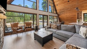 A spacious living room with large windows, a wooden ceiling, and a cozy seating area.