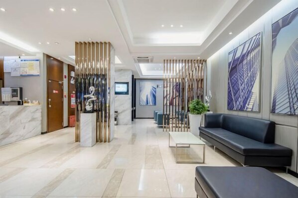 Um saguão de hotel com balcão de recepção, área de estar e uma grande janela com vista.