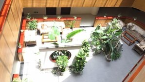 A spacious indoor area with a seating arrangement, potted plants, and a stone fireplace. - Lifeng Hotel (Zhaoping)