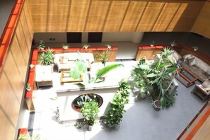 Une cour intérieure aménagée avec des espaces de détente, des plantes en pot et une fontaine centrale.