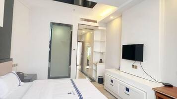 A modern hotel room with a bed, bedside table, TV, and built-in wardrobe.